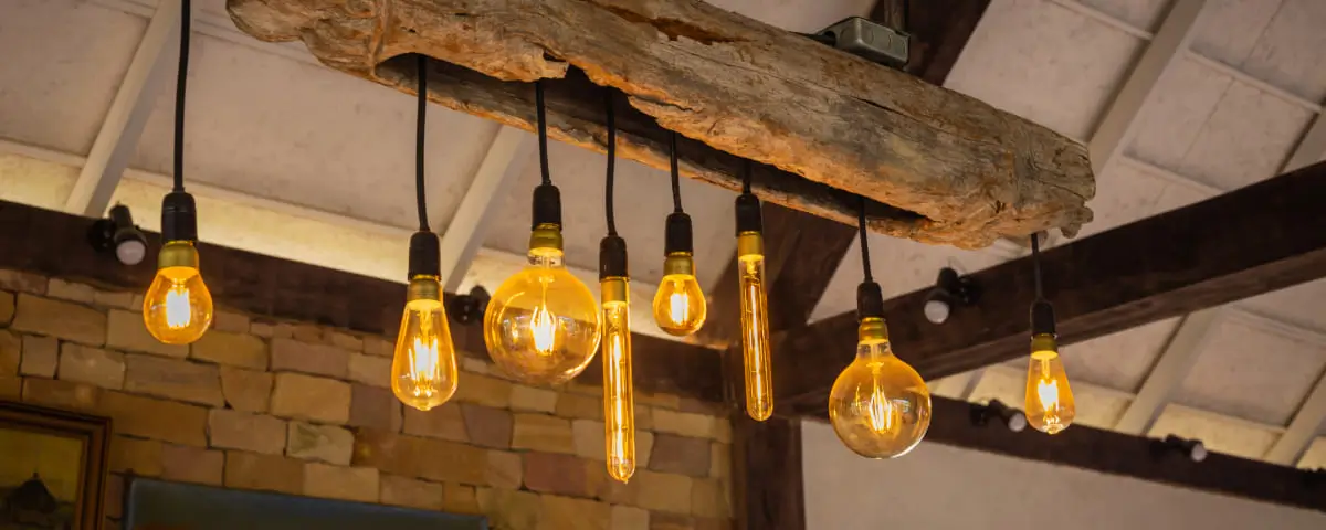 Ampoules incandescentes décoratives avec du bois et sur fond de mur en brique.