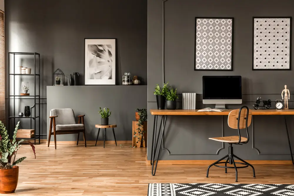 Affiches à motifs au-dessus du bureau avec écran d'ordinateur à l'intérieur du bureau à domicile gris avec plantes.